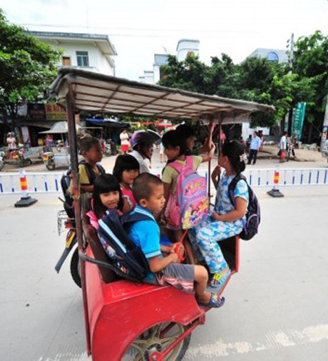 9月4日，新学期伊始，海南乐东县佛罗镇的小学生乘坐三轮车上下学。坐在这种被当地人称作“风采车”改装摩托车上。有一辆三轮车上甚至坐了8名孩子。